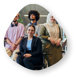 A diverse group of six people, including a woman in a wheelchair, standing and smiling in an office environment, representing inclusivity and teamwork.