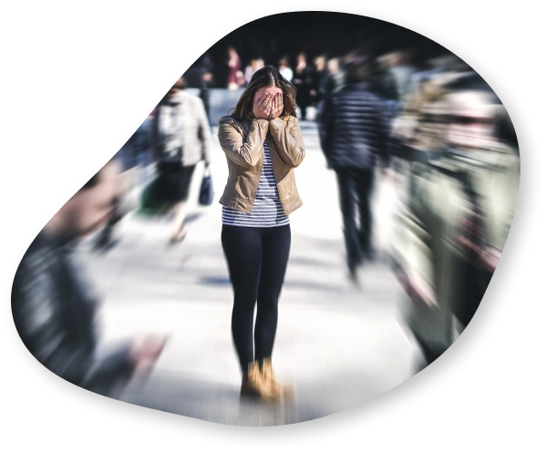 A woman standing in a busy street with her hands covering her face, surrounded by a blurred crowd, symbolizing anxiety and feeling overwhelmed.